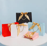 Bolsa de papel con logotipo personalizado al por mayor con lazo para ropa, bolsa de papel de lujo con asa y lazo para compras.