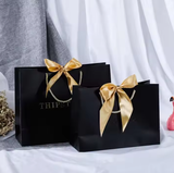 Bolsa de papel con logotipo personalizado al por mayor con lazo para ropa, bolsa de papel de lujo con asa y lazo para compras.